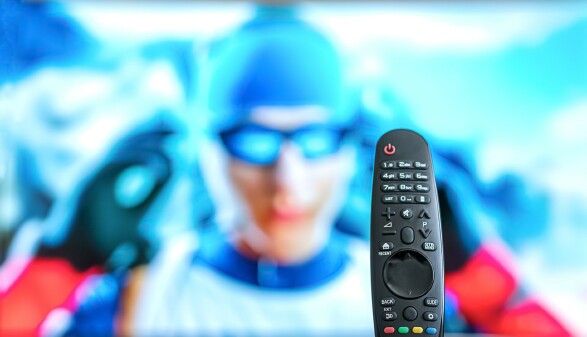 Schwarze TV-Fernbedienung auf dem Tisch, Biathlon oder Skirennen l&auml;uft im Hintergrund