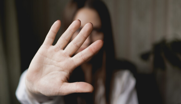 Unscharf abgebildete Frau hält ihre Hand als Stoppsignal in die Kamera