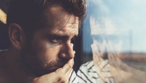 Junger Mann blickt traurig aus dem Fenster