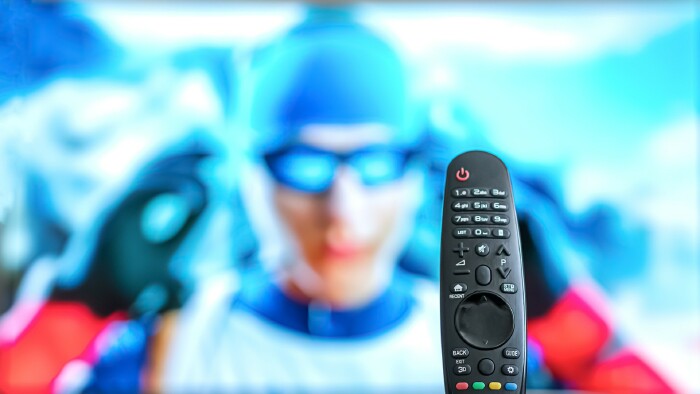 Schwarze TV-Fernbedienung auf dem Tisch, Biathlon oder Skirennen l&auml;uft im Hintergrund