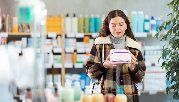 Junge Frau kauft Damenhygieneartikel