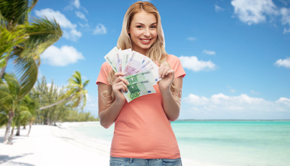 Junge Frau mit Geldscheinen, im Hintergrund Palmenstrand