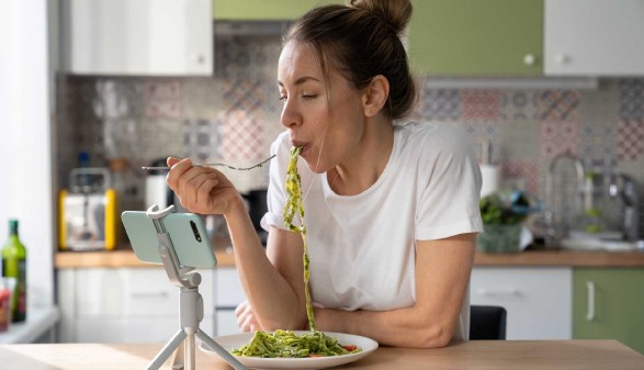Frau isst Nudeln mit Basilikum-Pesto