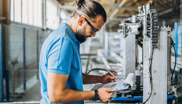 Arbeiter mit Klemmbrett in Produktionshalle